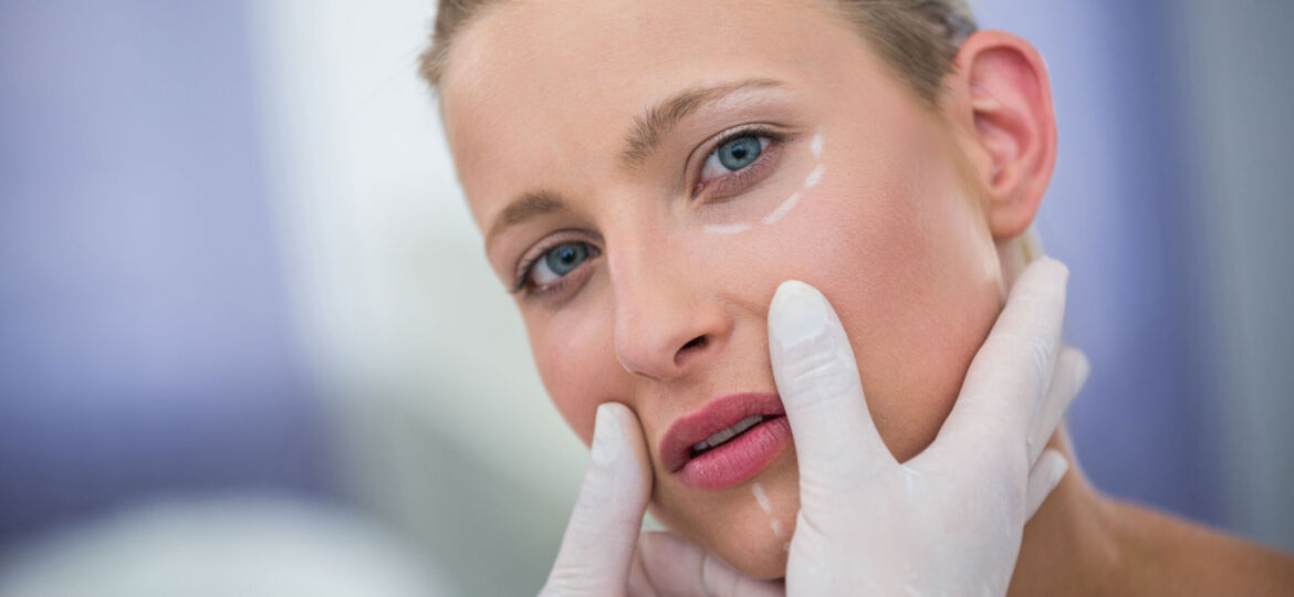 Close-up of doctor examining female patients face for cosmetic treatment